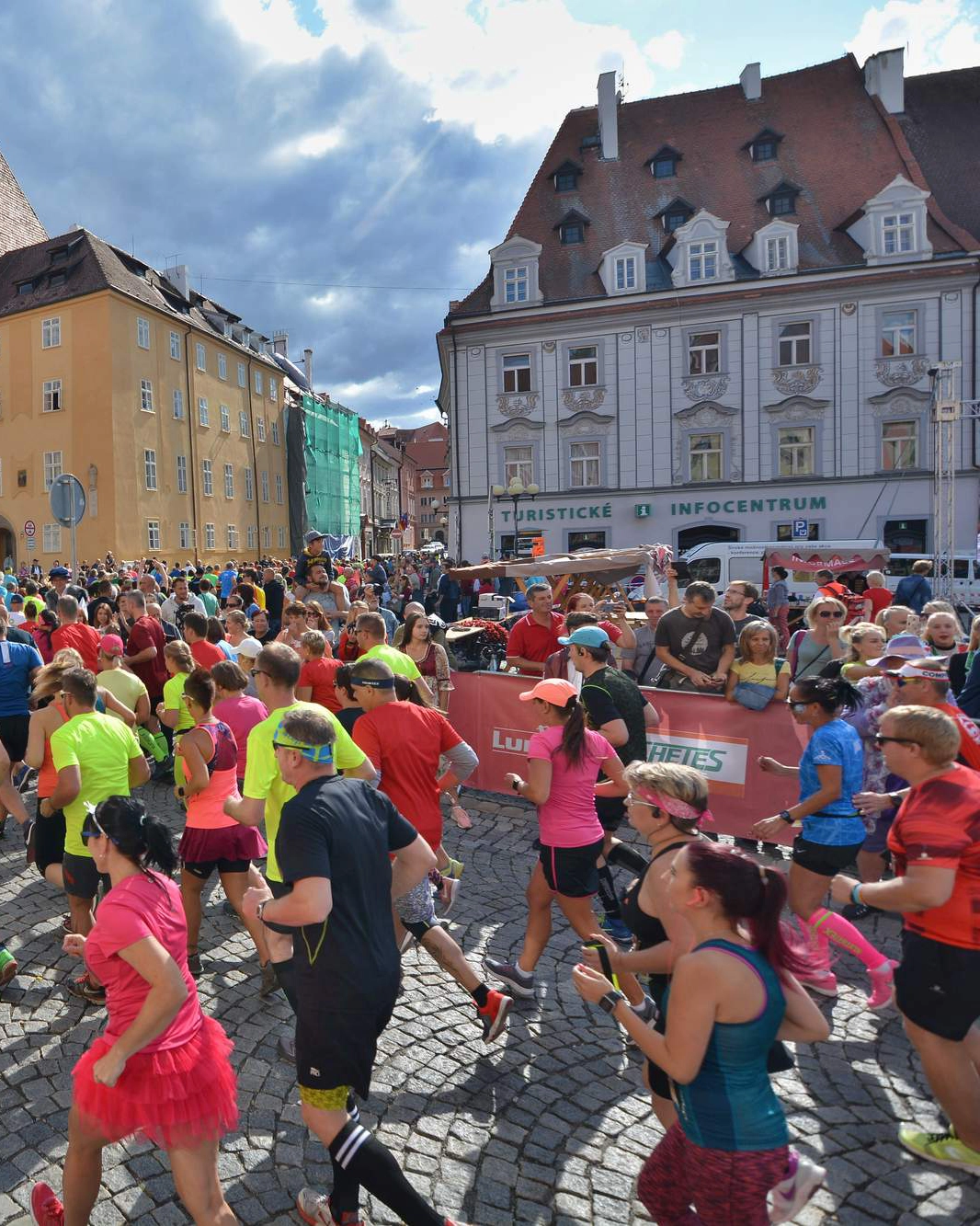 Běžci probíhají kolem Špalíčku, po stranách tleskající diváci